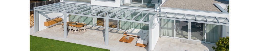 Eine moderne Überdachung mit Glas-Elementen und Terrassensituation, rechteckige Form, helle Farben.