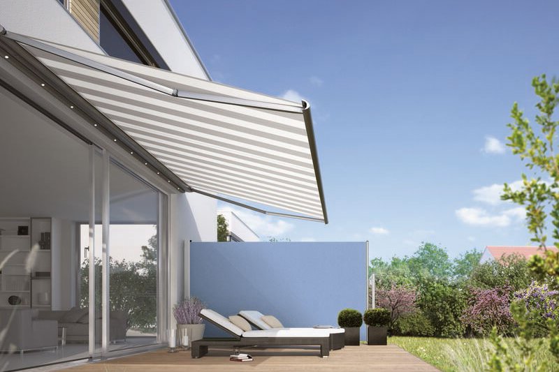 Sonnenschutz in Form einer Markise über einer Terrassensituation mit Liegen und grüner Umgebung.