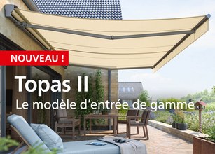 Marquise beige étendue au-dessus d'une terrasse, avec mur en pierre et mobilier d'extérieur. 