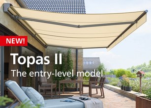 A stylish cream awning extending over a terrace with seating and greenery in the background. 