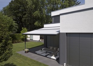 Moderne Architektur mit einer Überdachung und Terrassensituation in grünem Umfeld. 