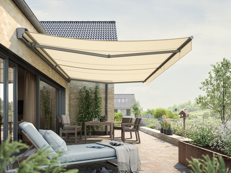 Markise in hellem Beige über einer Terrassensituation mit Sitzgelegenheiten und Pflanzen im Hintergrund.