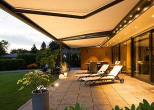 Sonnige Terrassensituation mit Markisen und elegantem Beleuchtungskonzept. 