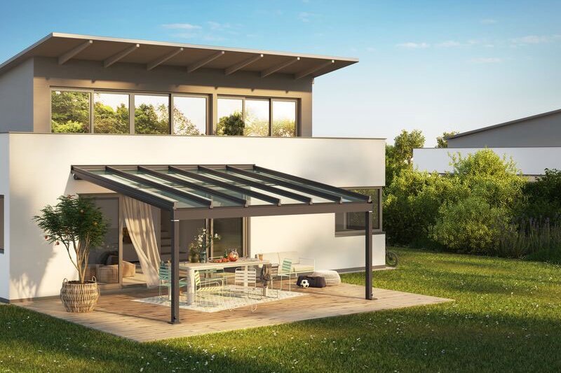 Moderne Überdachung mit Glas-Schiebewänden und Terrassensituation in grünem Garten.