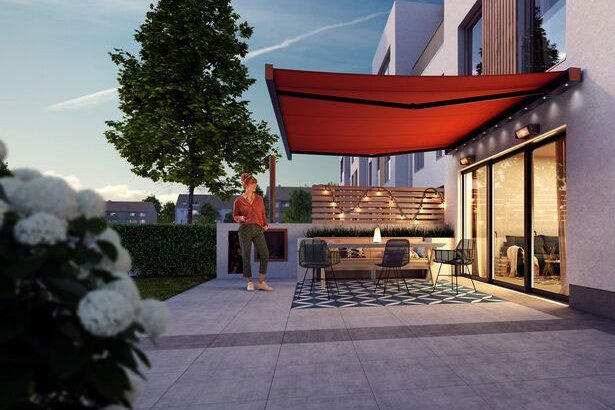 Sonnenschutz in Rot über einer modernen Terrassensituation mit Sitzbereich und Pflanzen im Vordergrund. Sonnenschutz in Rot über einer modernen Terrassensituation mit Sitzbereich und Pflanzen im Vordergrund.