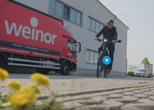 Screenshot Video Mann fährt mit einem Fahrrad und im Hintergrund steht ein weinor LKW 