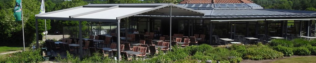 Terrassensituation mit Markisen und Überdachung, umgeben von grünen Pflanzen und Möbeln.
