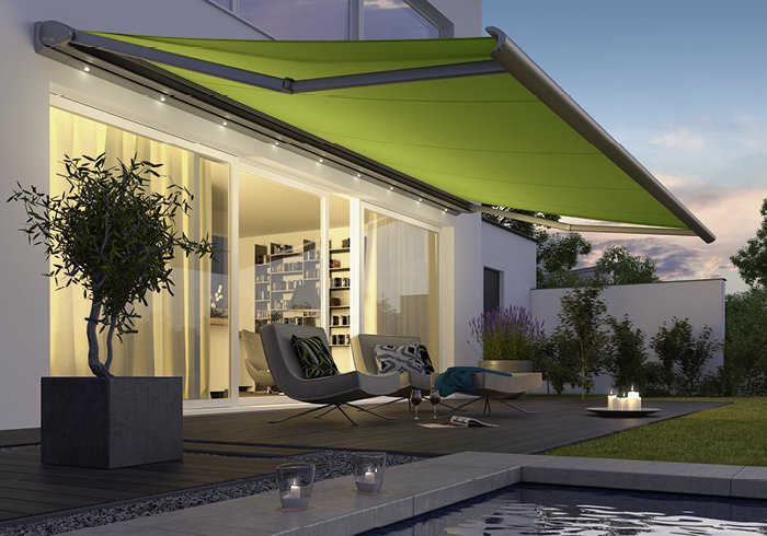 Markise in leuchtendem Grün über einer Terrasse mit modernem Interieur und Pflanzen.